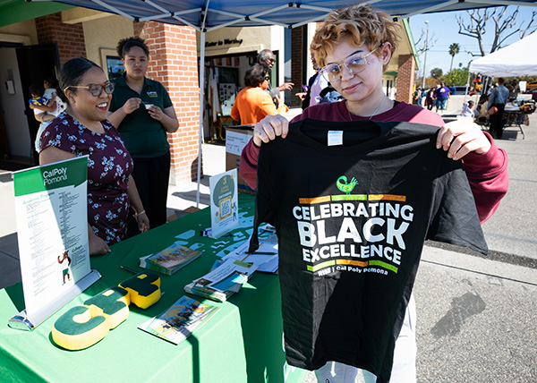A girl holds a Celebrating Black Excellence tshirt 